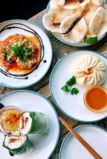 Overhead shot of various Asian dishes on a rustic wooden table.