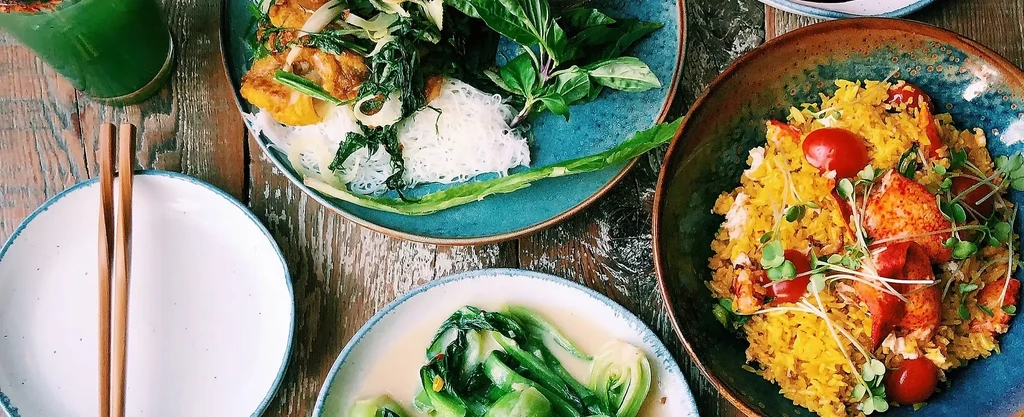 Overhead: Vibrant dishes, including lobster, green vegetables, and a drink.