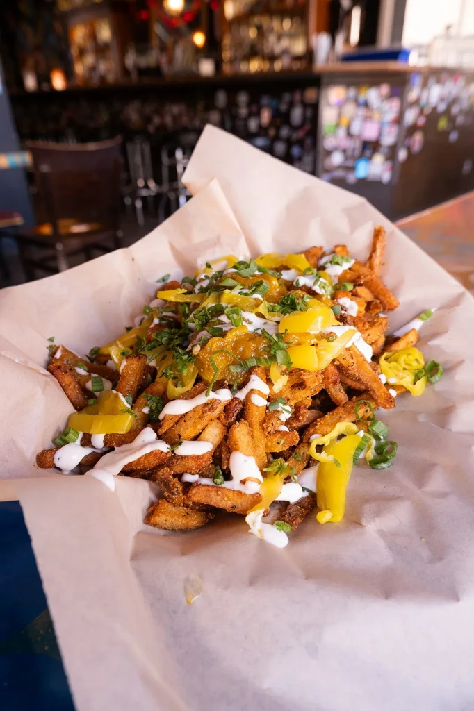 Loaded fries with creamy sauce, relish, peppers, and green herbs.