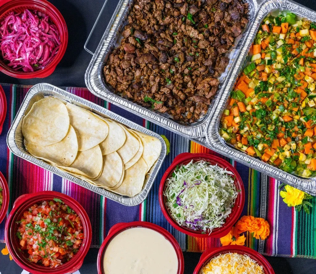 Overhead view of a vibrant Mexican food buffet on a striped blanket.