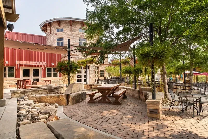 Paved outdoor patio with stone walls, string lights, and distinct buildings.