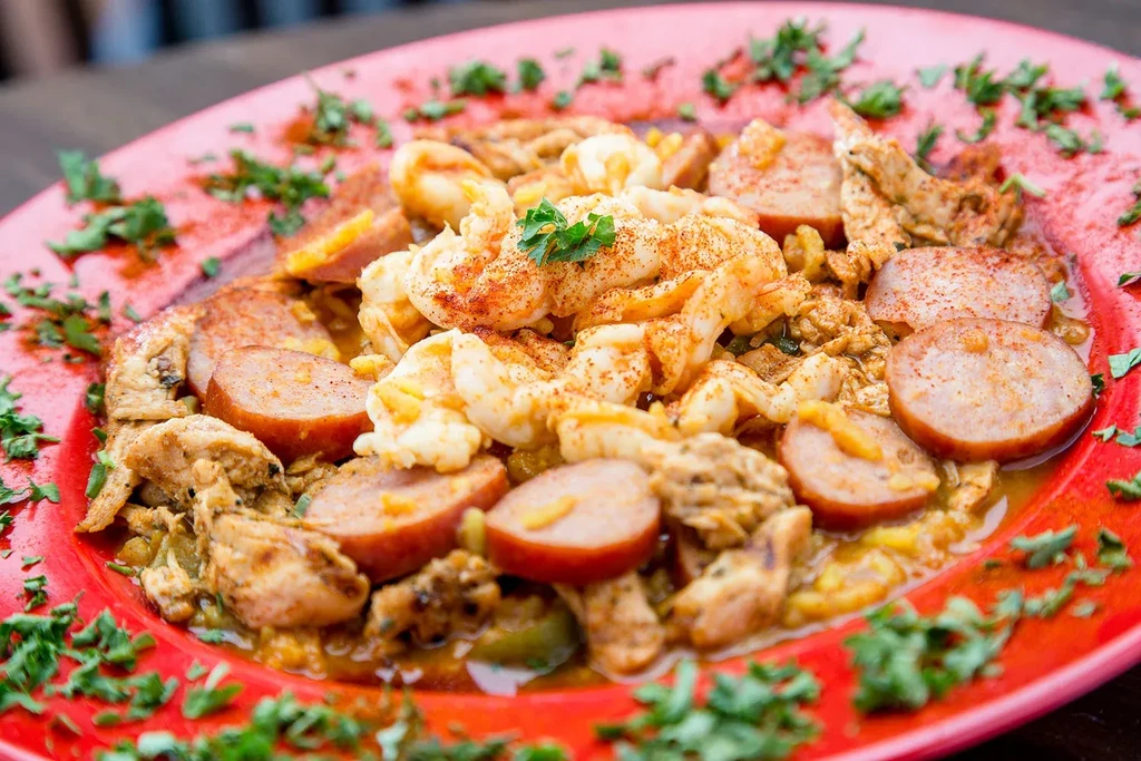Close-up of shrimp, sausage, and chicken jambalaya on a red plate.