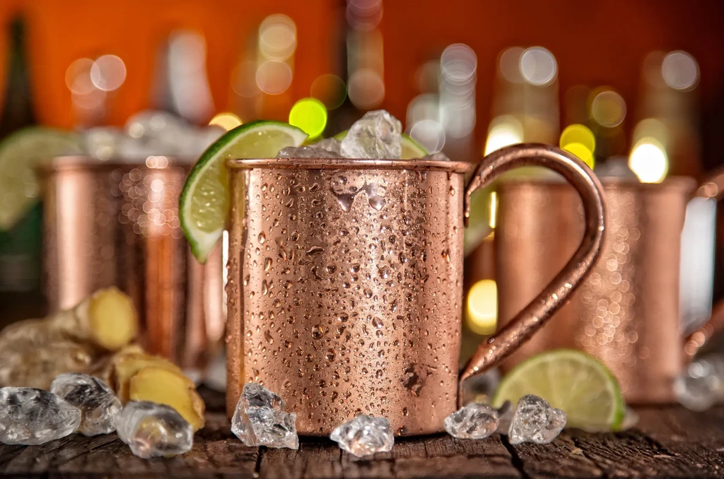 Multiple frosty Moscow Mules in copper mugs with lime and ginger.
