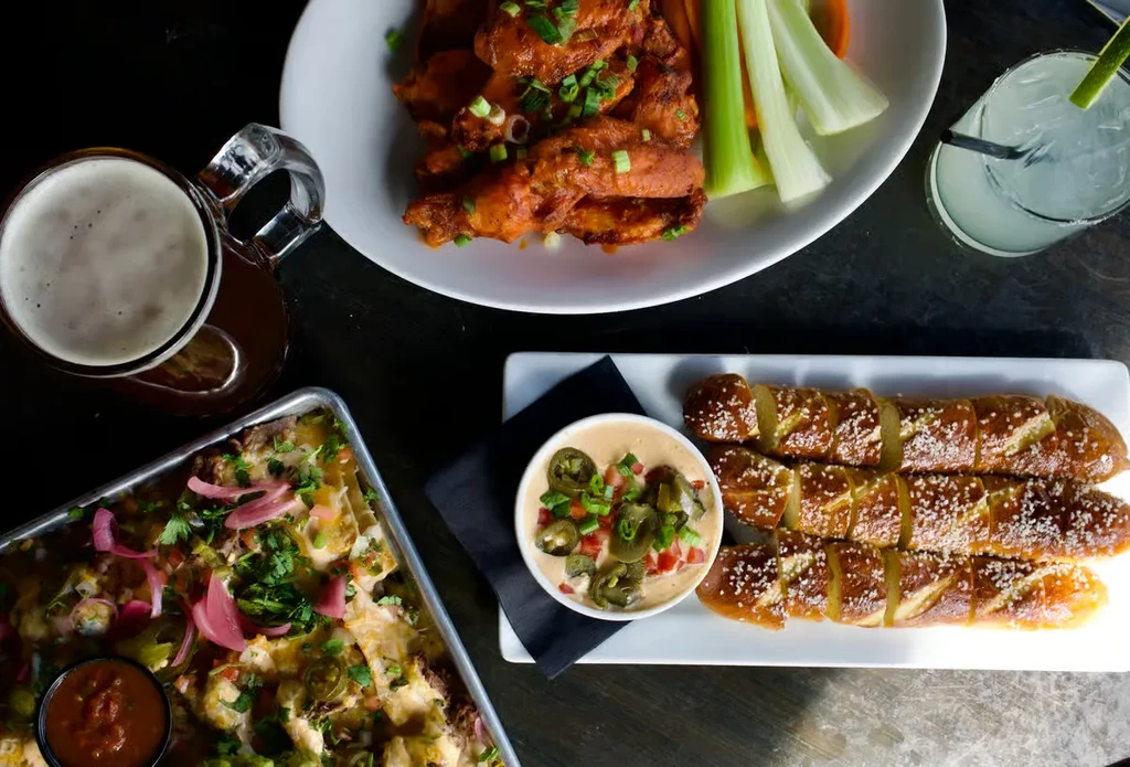 Overhead view of various appetizers and drinks on a dark table.