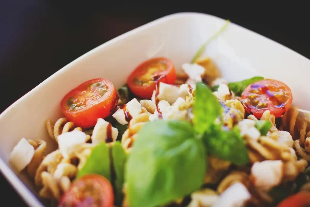 Pasta salad with tomatoes, mozzarella, basil, and balsamic glaze.