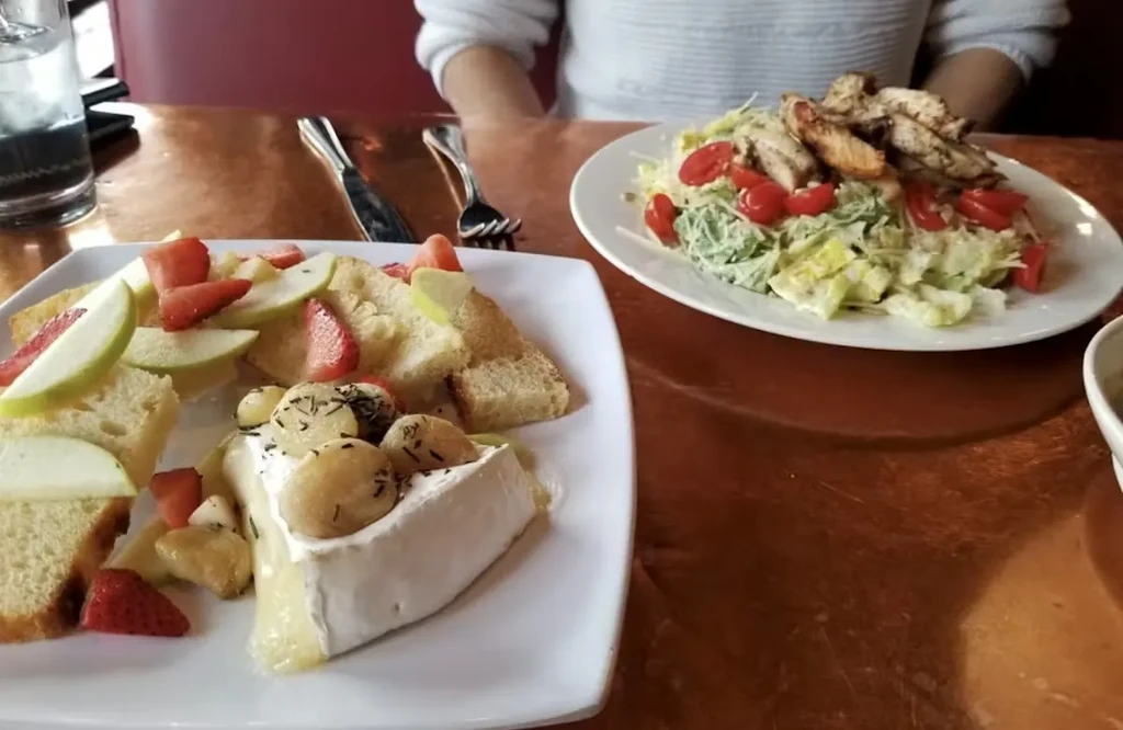 Two restaurant plates: baked brie appetizer and grilled chicken salad.