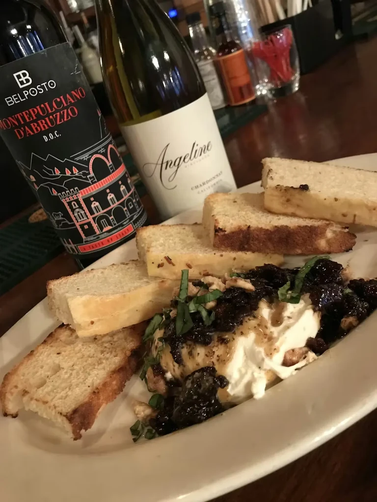 Creamy cheese with compote and toast, beside Montepulciano and Chardonnay.