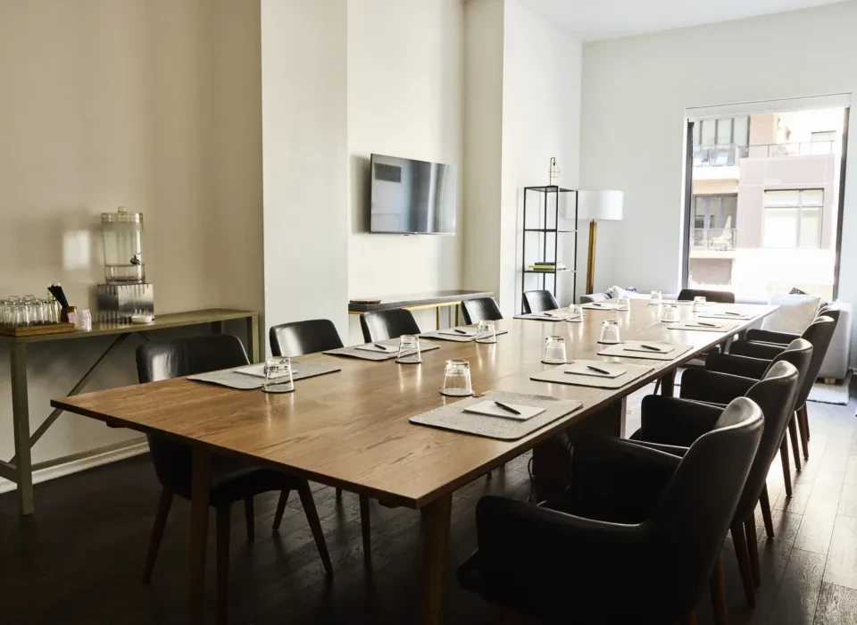 Well-lit, empty modern meeting room with a long table and chairs.