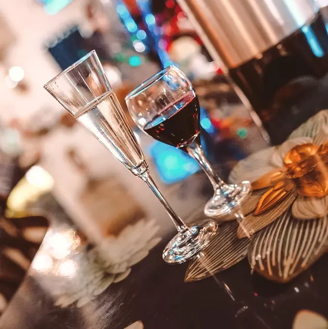 Fluted glass with clear drink, wine glass with red wine.