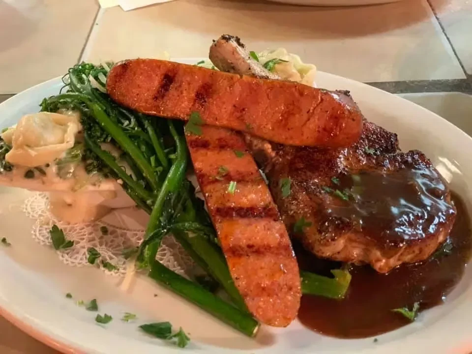 Well-plated meal: meat with gravy, sausage, broccolini, and pasta.