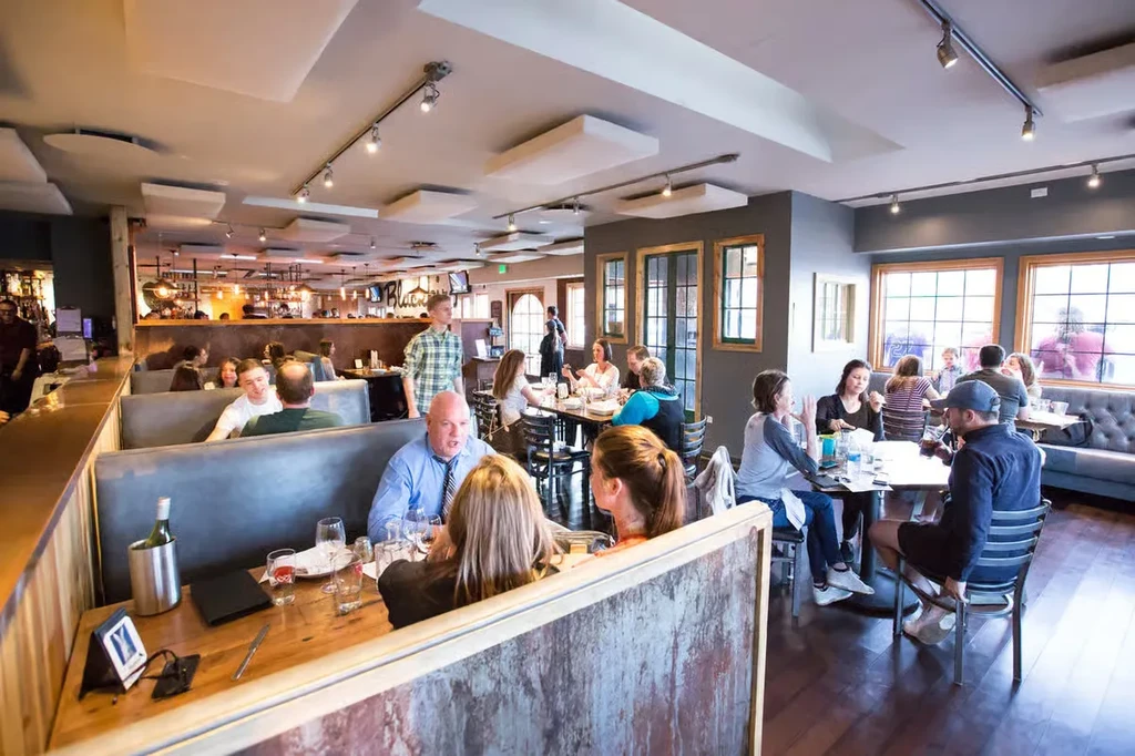 Bustling modern restaurant interior with many diners and wooden accents.