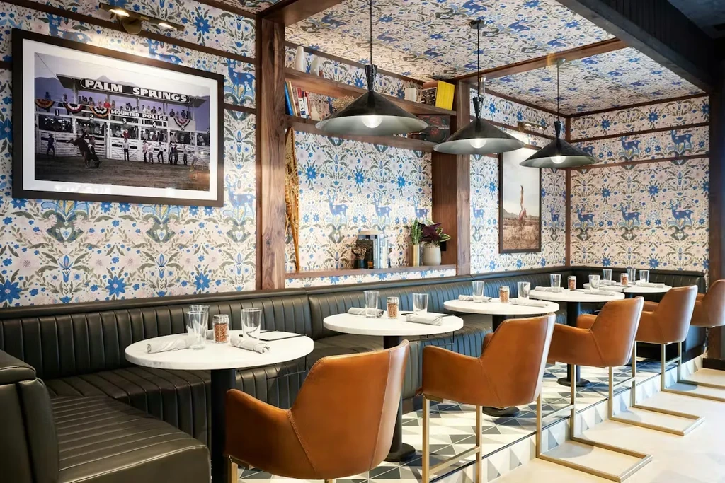 Stylish restaurant interior with intricate blue floral and deer wallpaper.