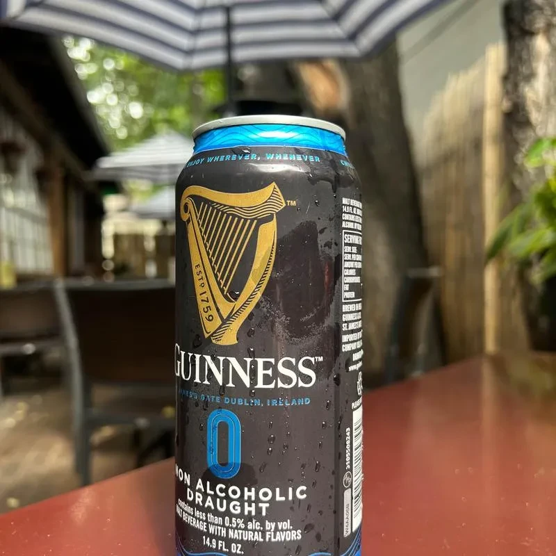 Cold Guinness 0% beer can with condensation on outdoor table.