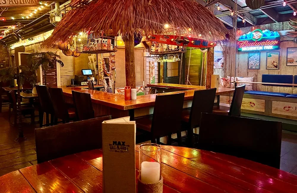 Dimly lit tropical restaurant interior with a large thatched tiki bar.