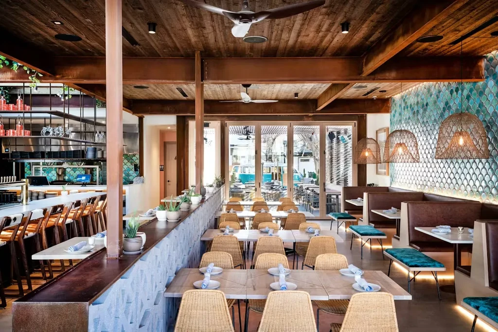 Empty restaurant interior with wooden ceiling and teal fish-scale tiles.
