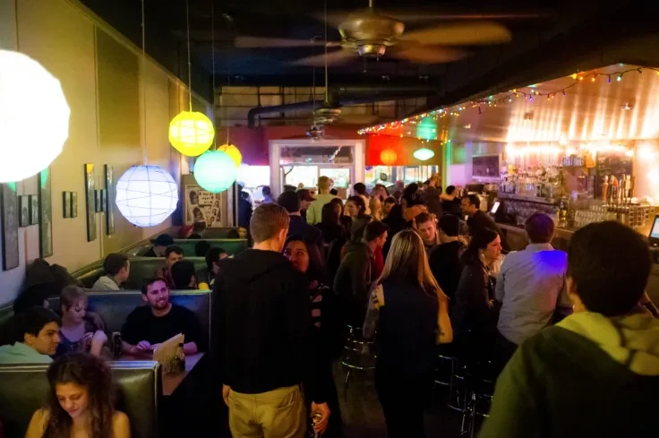Lively restaurant bar filled with colorful lanterns and many people.