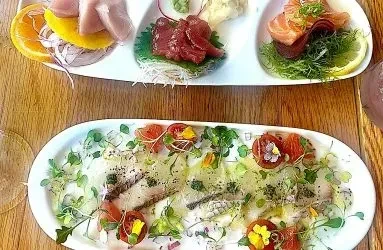Overhead view of a sushi platter and fish carpaccio with edible flowers.