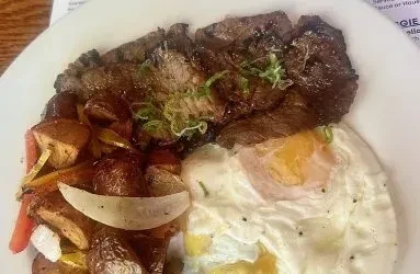 Grilled steak, roasted potatoes, vegetables, and a fried egg.