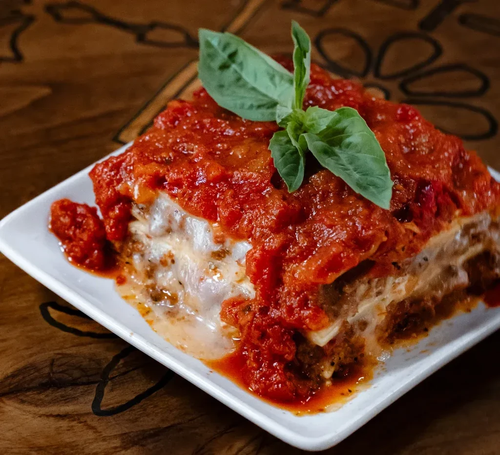 Lasagna slice with chunky red sauce, basil, and melted cheese.