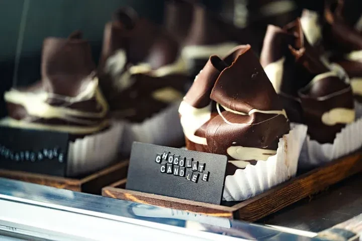 Several dark chocolate desserts with white swirls; small "CHOCOLATE CANDLE" sign.