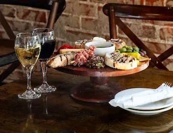 Charcuterie platter on a tiered stand, with wine and place settings.