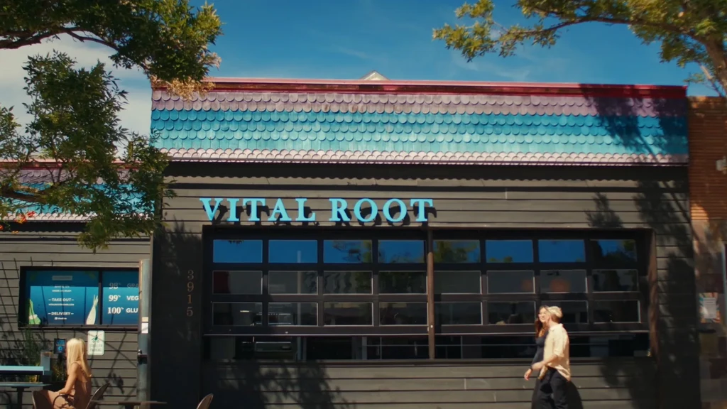 Sunny exterior of Vital Root restaurant with multi-colored scalloped awning.