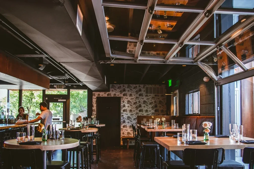 Modern restaurant interior with diverse seating, industrial decor, and natural light.
