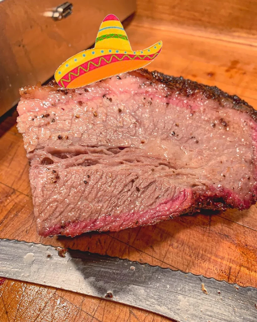 Thick brisket slice with smoke ring, crust, and tiny sombrero.
