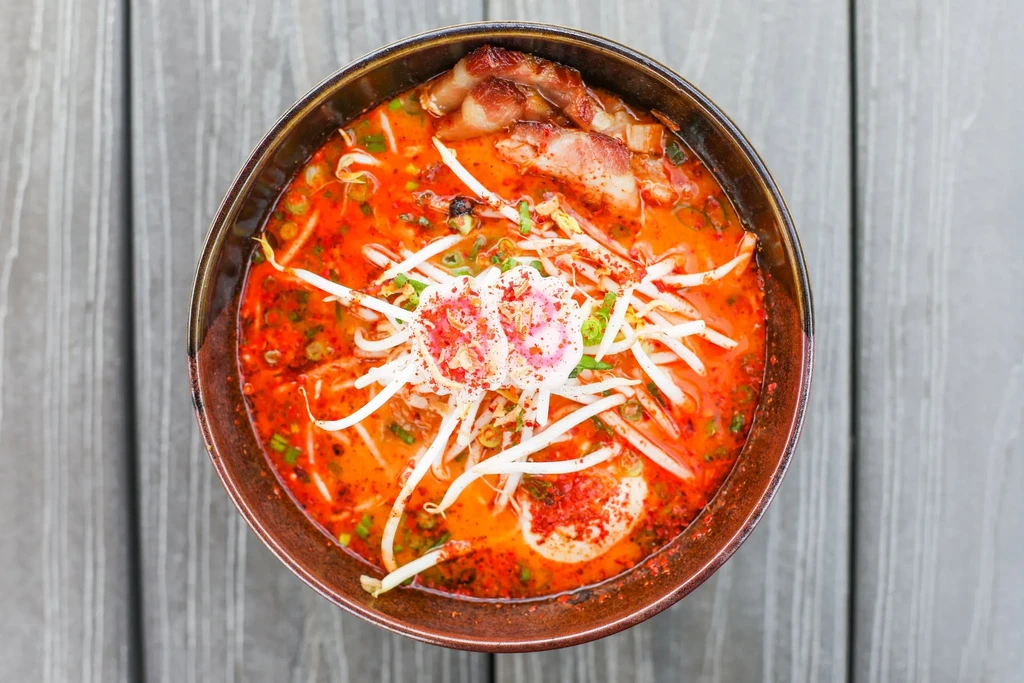 Vibrant overhead shot of spicy ramen with pork belly, egg, narutomaki.