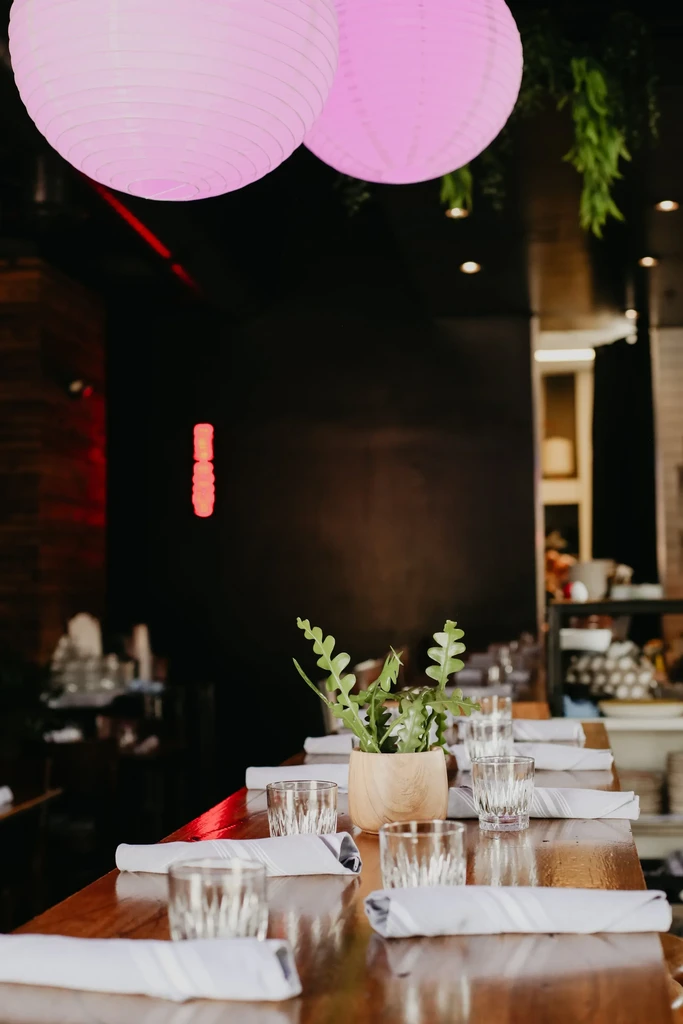 Set wooden table under pink lanterns in a modern restaurant.