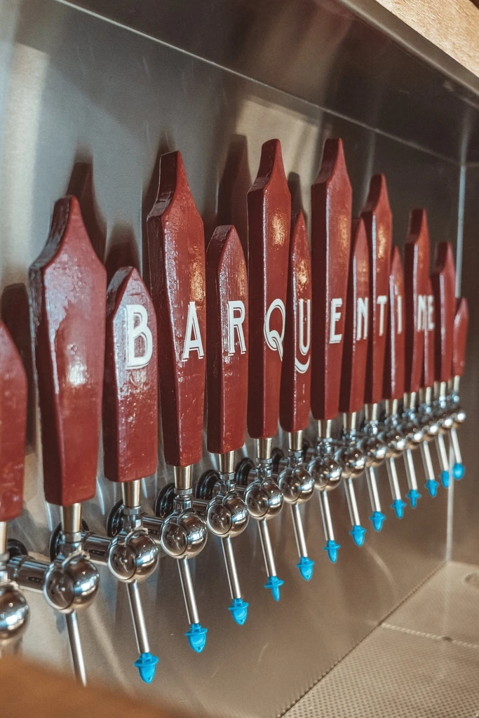 Reddish-brown beer taps spelling BARQUENTINE, with blue caps.