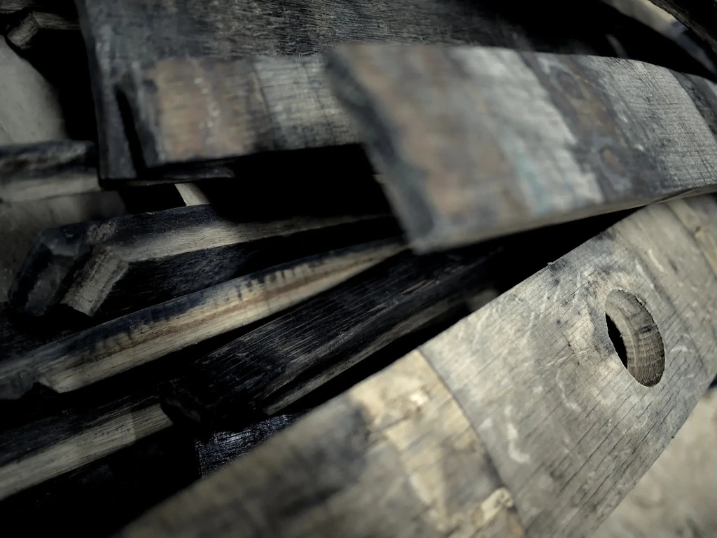 Close-up of weathered wooden barrel staves, charred, with a visible bung hole.