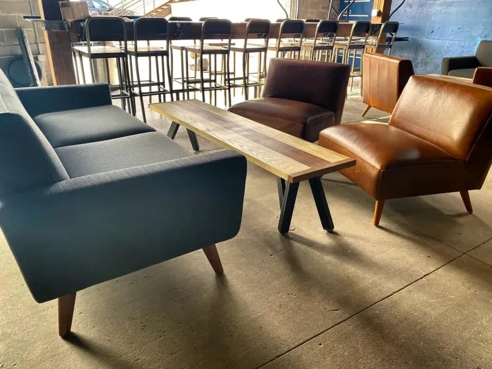 Industrial lounge with gray sofa, wood table, and leather armchairs.