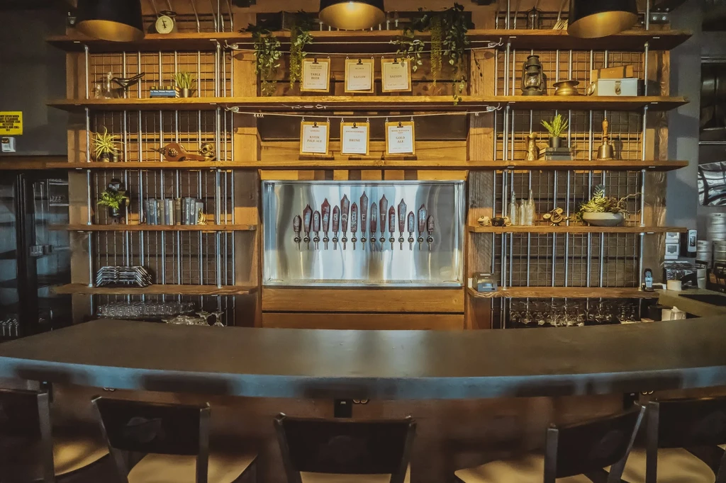Industrial-chic bar with numerous beer taps and decorated wood shelving.