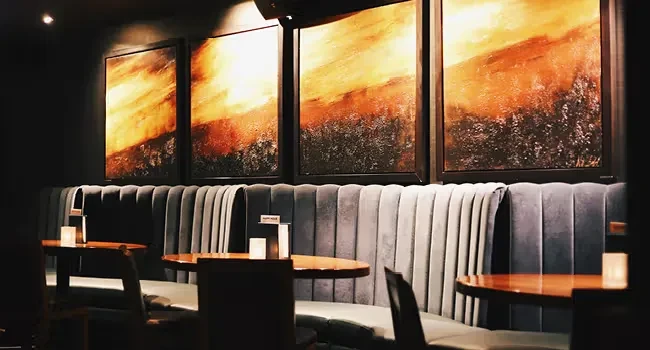 Plush dark velvet booth seating under abstract art and dim lights.