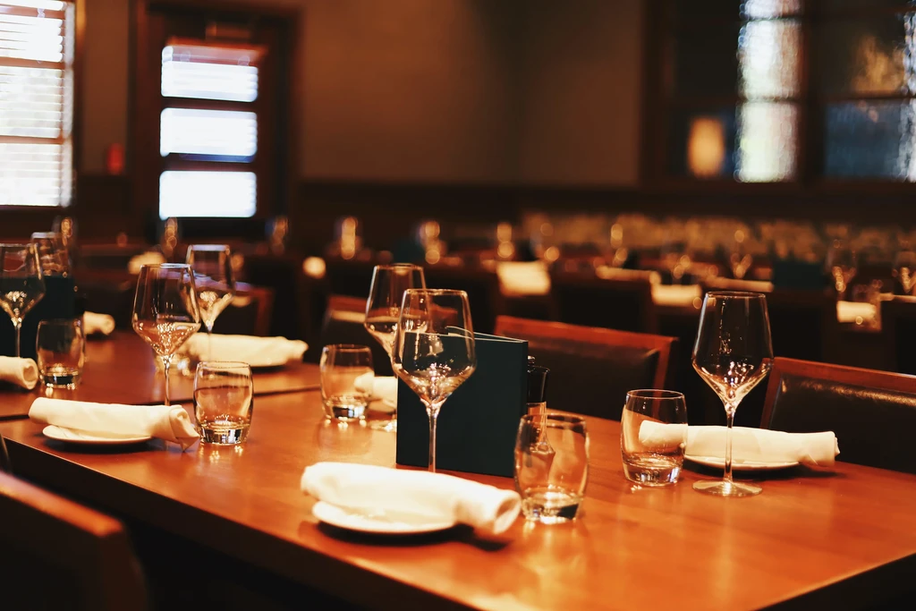 Elegantly set restaurant table with glasses, napkins, in warm light.