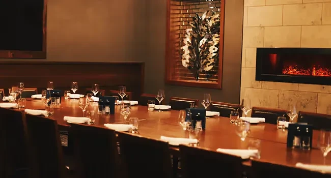 Private dining room with a set table, electric fireplace, and art.