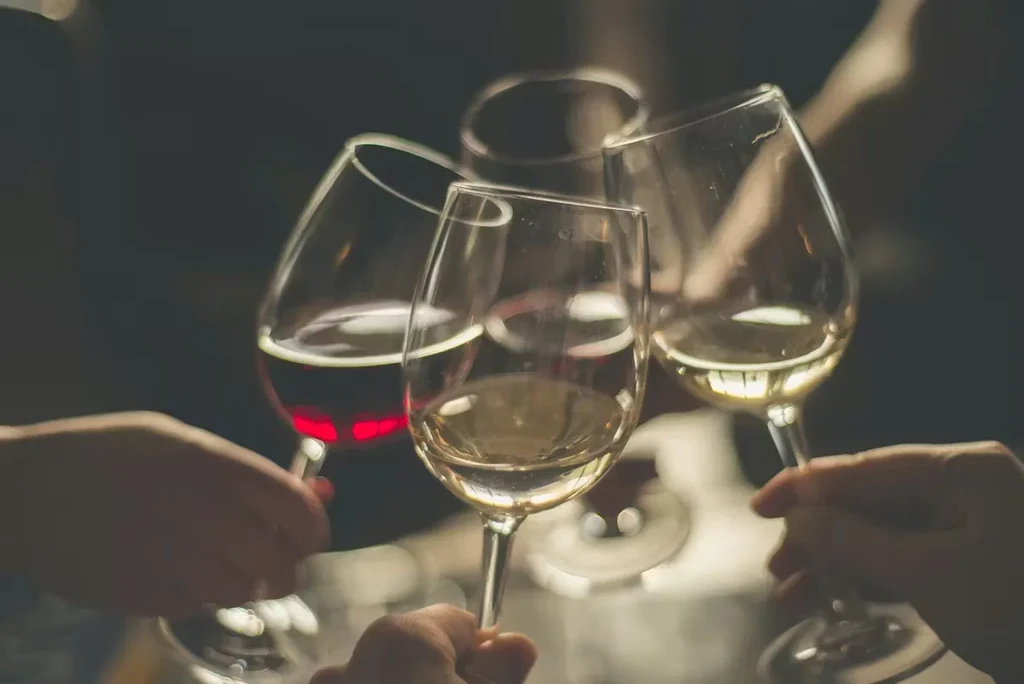 Four wine glasses, two red and two white, held in a toast.