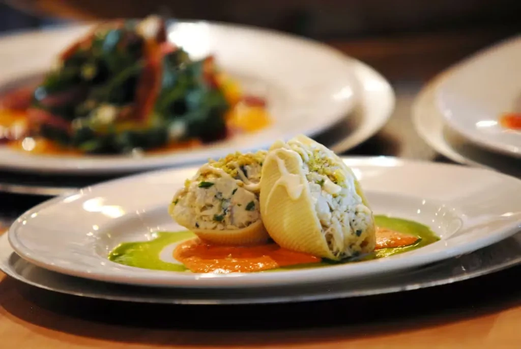 Two stuffed pasta shells with creamy filling, orange-red and green sauces.