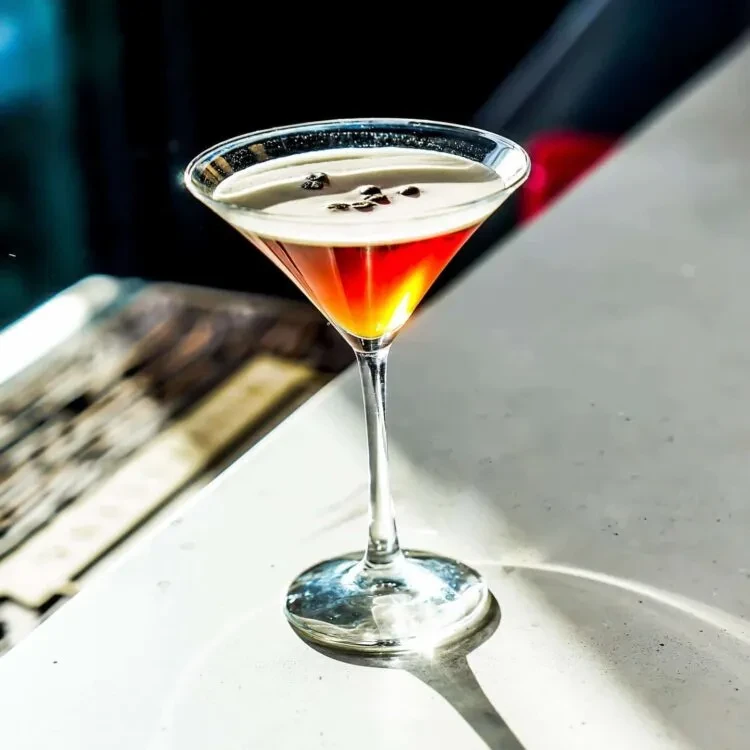 Two-toned cocktail in a martini glass with coffee bean garnish.