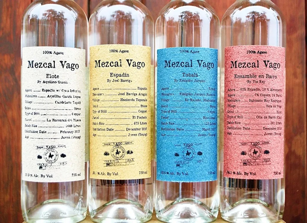 Four Mezcal Vago bottles with colorful, detailed paper labels.