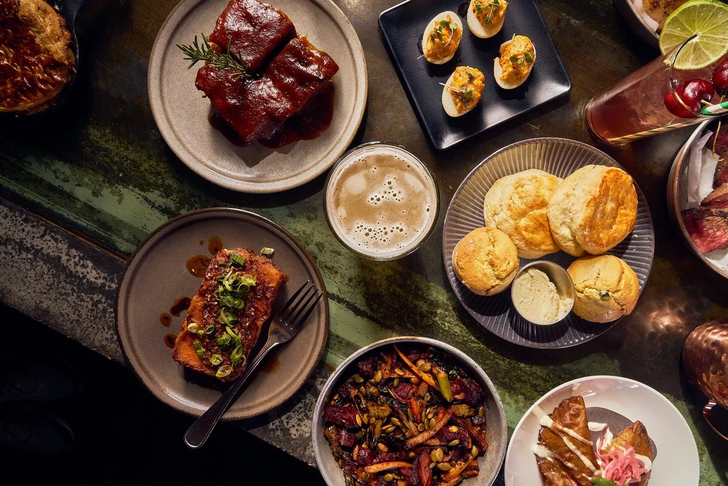 Overhead shot of diverse gourmet dishes and drinks on a rustic table.