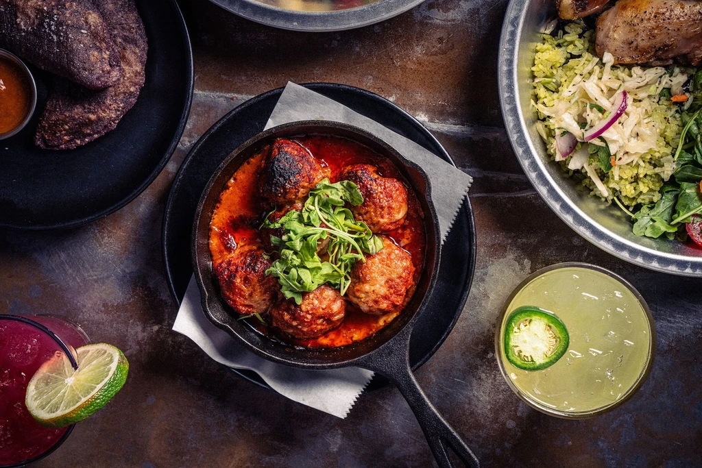 Overhead shot of a rustic table with diverse dishes and cocktails.