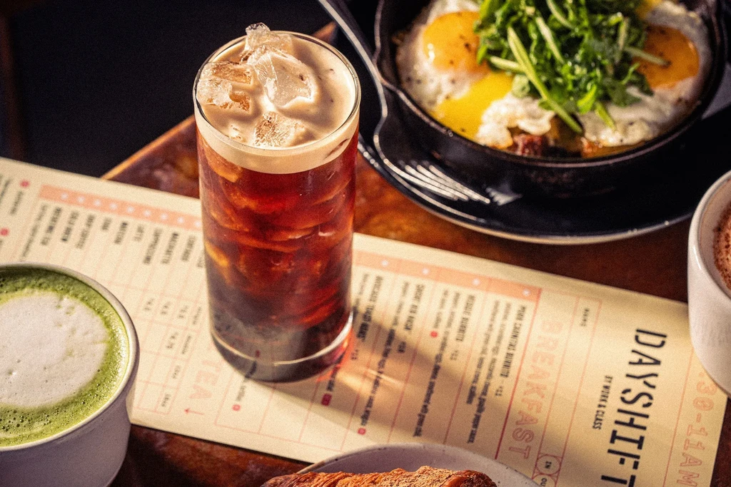 Iced coffee, matcha latte, fried eggs, and menu on a wooden table.