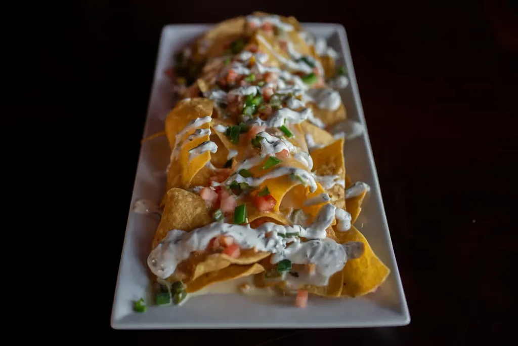 Crispy nachos with melted cheese, white sauce, tomatoes, and green onions.