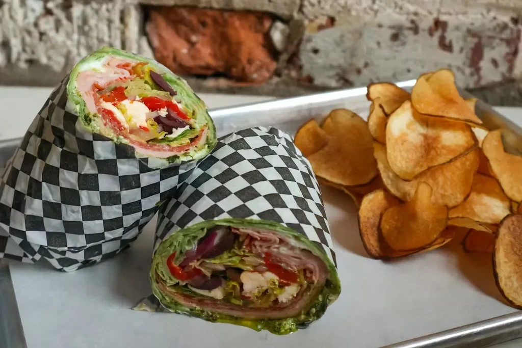 Green wraps filled with deli meat, vegetables, cheese, and chips.