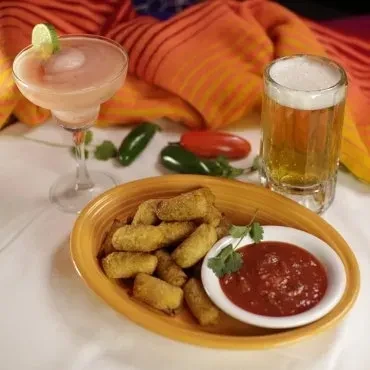 Appetizers, margarita, beer, and peppers on a table with a striped cloth.