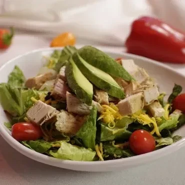 Grilled chicken salad with avocado, cheese, and cherry tomatoes.