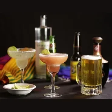 Cocktails, beer, and liquor bottles arranged with colorful striped fabric.