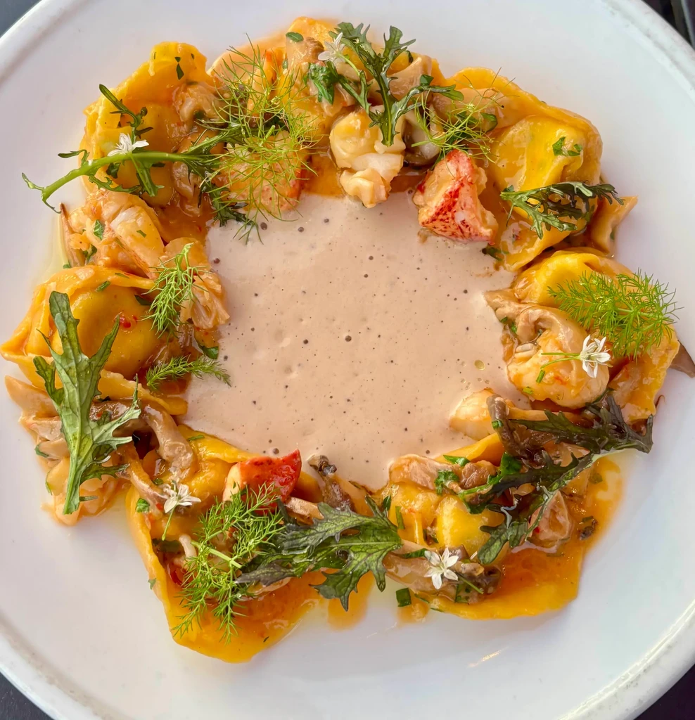 Circular golden pasta with lobster, mushrooms, fennel, and two sauces.